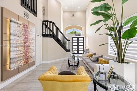 A living room with a yellow chair and a glass table.