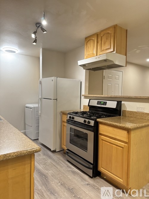 A kitchen with a white refrigerator, a black stove, and wooden cabinets.