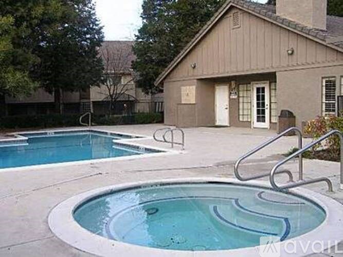 A small pool with a hot tub in front of a house.