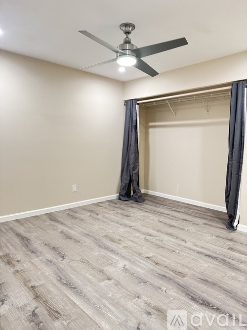 A room with a ceiling fan and a grey carpet.