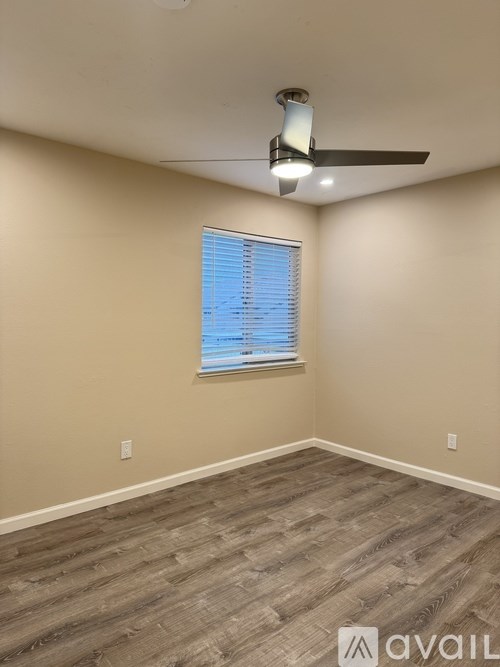 A room with a ceiling fan and a window with blinds.