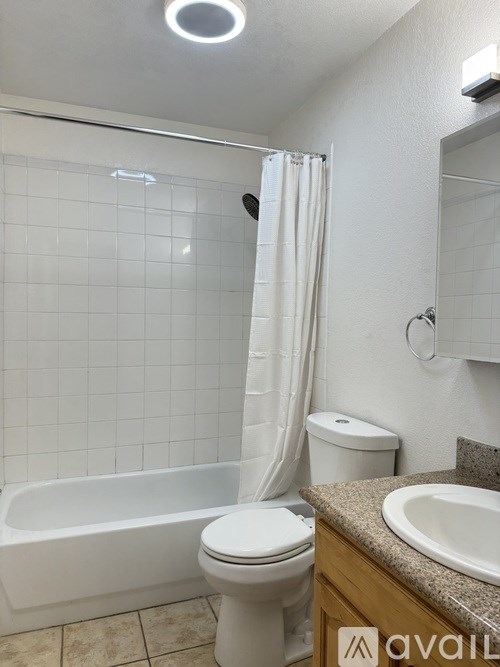 A white toilet sits next to a white bathtub in a bathroom.