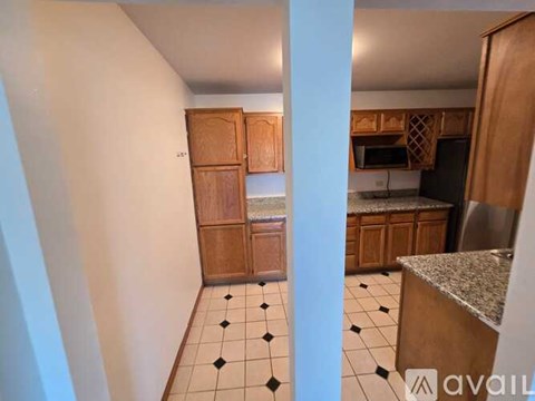 A kitchen with wooden cabinets and black and white tiles.