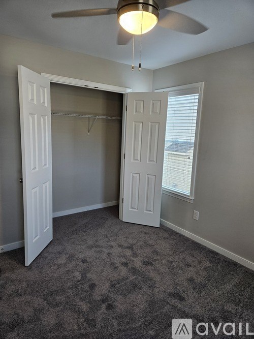 A room with a ceiling fan and a doorway leading to another room.