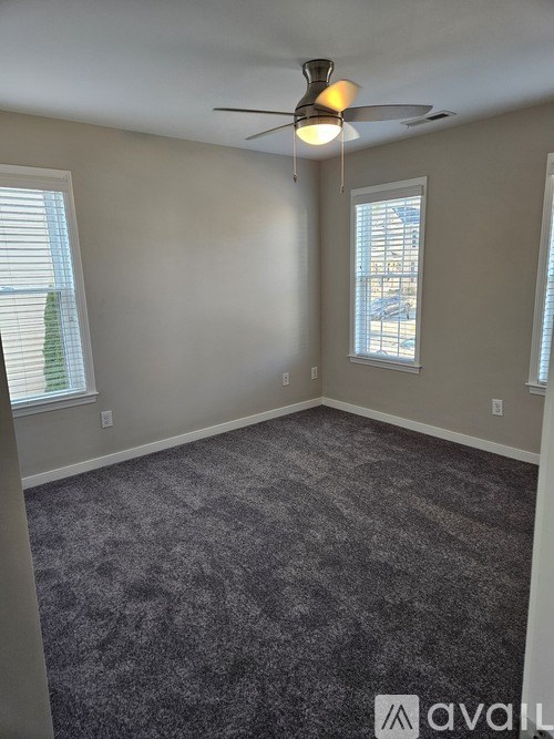 A room with a ceiling fan and carpeted floor.