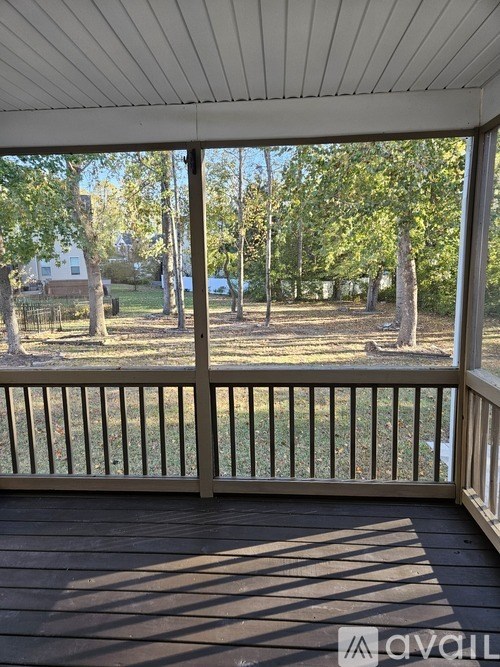 A deck with a railing and a view of a yard and trees.