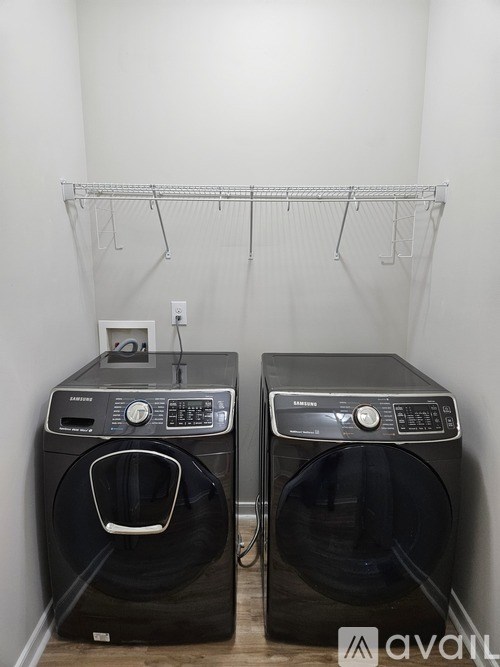 Two black front loading washing machines in a laundry room.
