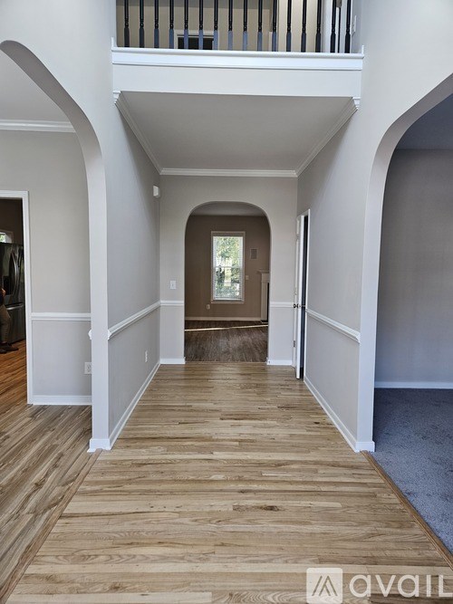 A hallway with wooden floors and white walls.