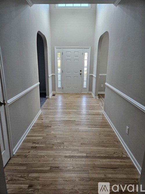 A hallway with wooden floors and white walls.