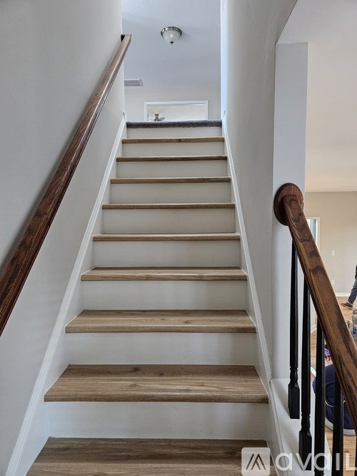 A wooden staircase with a black railing.