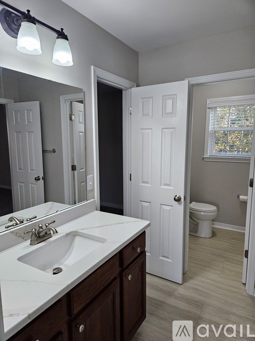 A bathroom with a sink, mirror, and toilet.