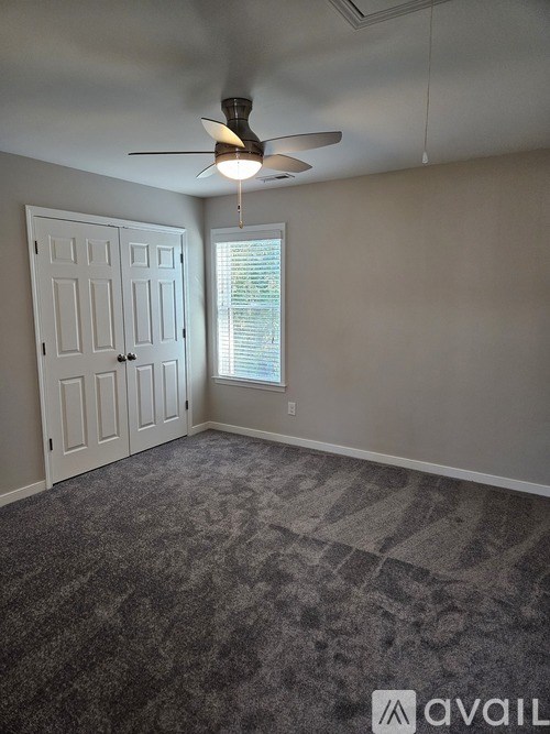 A room with a ceiling fan and a door.