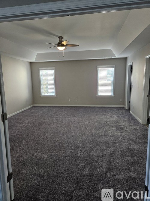 A room with a ceiling fan and carpeted floor.