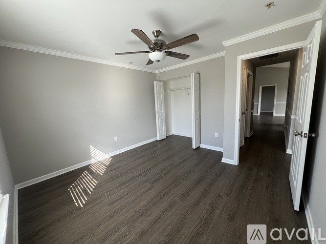A room with a ceiling fan and wood flooring.