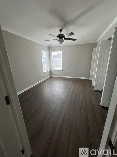 A room with a ceiling fan and wooden flooring.
