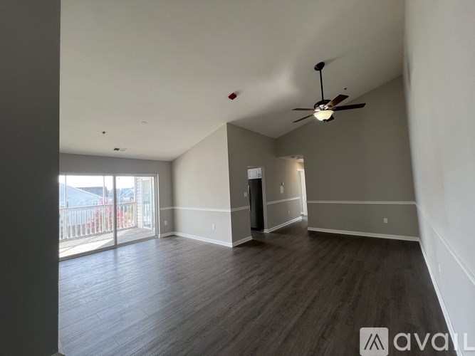 A spacious room with a ceiling fan and wooden flooring.