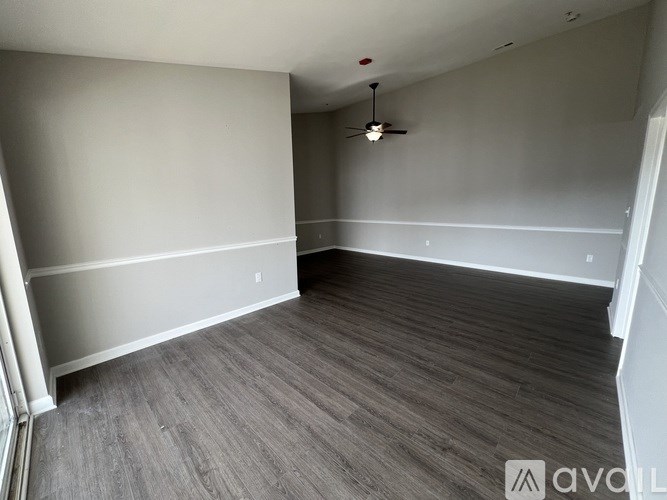 A room with a ceiling fan and wooden flooring.