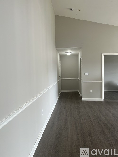 A hallway with a door at the end and a mirror on the wall.