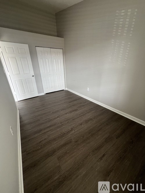 A room with wooden flooring and two white doors.