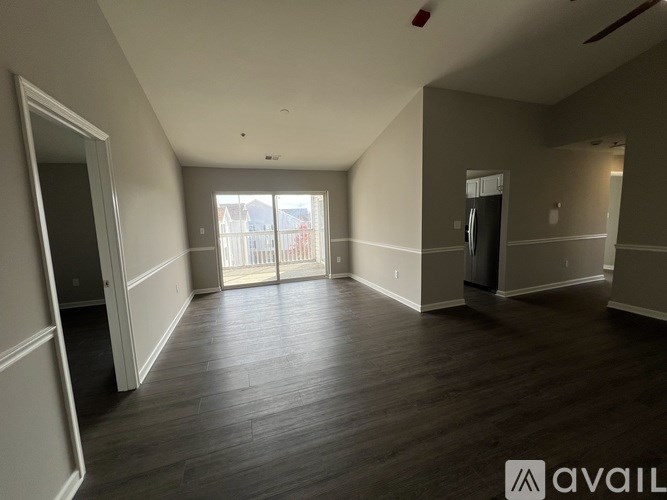 A spacious room with wooden flooring and a large window.