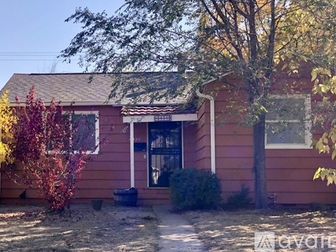 A red house with a tree in front of it.