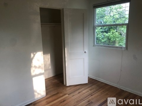A room with a white door and a window showing greenery outside.