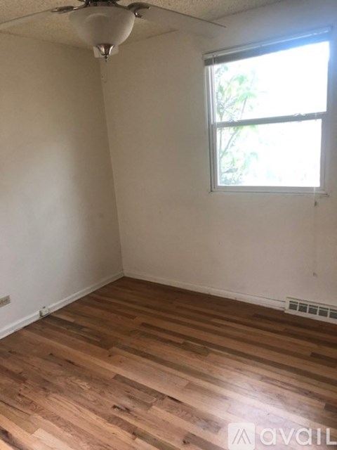 A room with wooden floors and a window letting in sunlight.