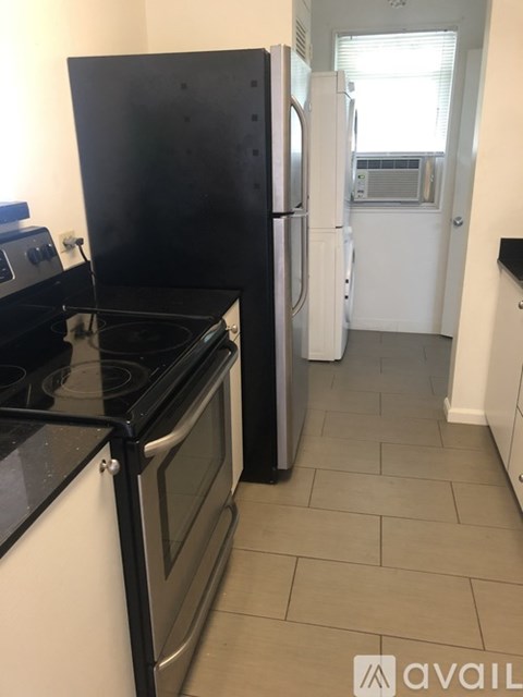 A kitchen with black and white appliances and a tiled floor.