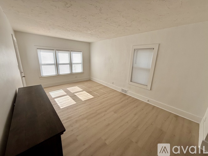 A room with wooden flooring and two windows is available for rent.