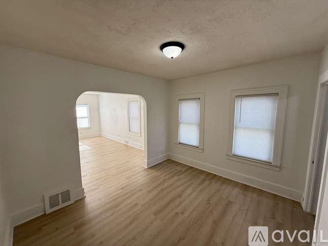 A spacious room with wooden floors and three windows.