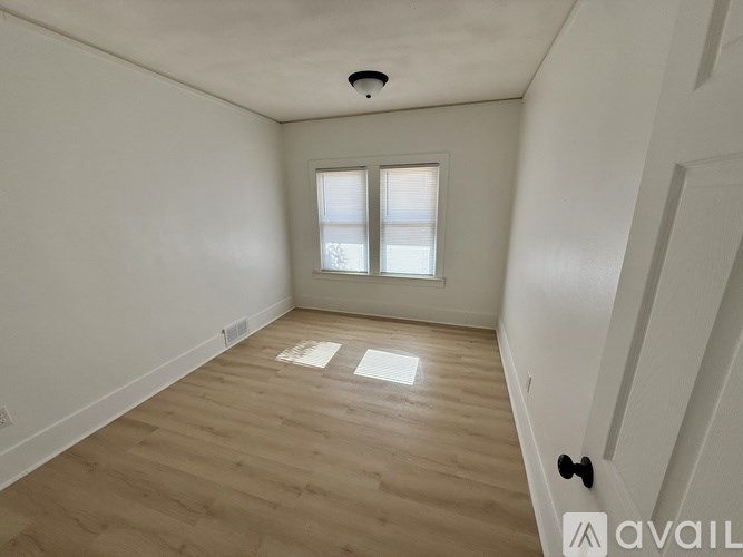 A room with wooden flooring and a window with blinds.