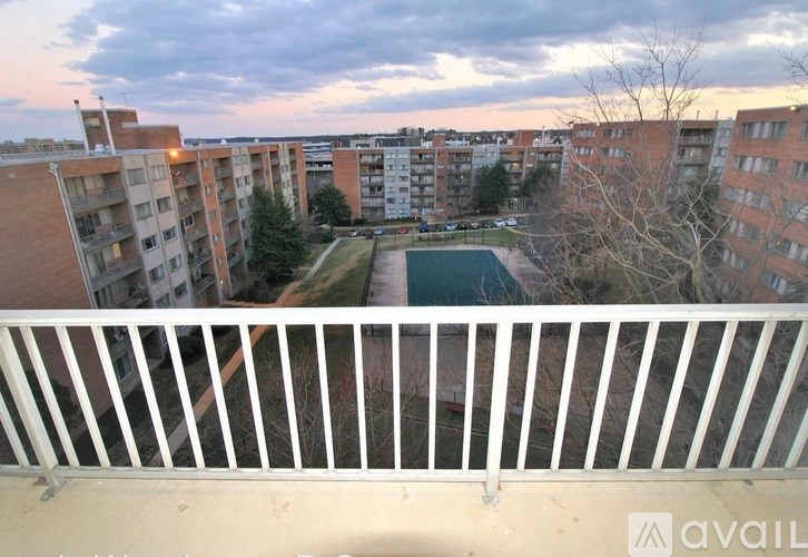 A view from a balcony overlooking apartment buildings and a green space.