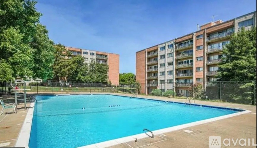 A swimming pool surrounded by trees and buildings.