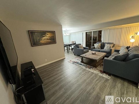 A living room with a grey couch, a coffee table, and a painting on the wall.