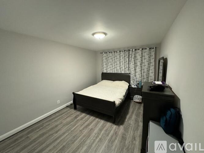 A bedroom with a bed, nightstand, and window with curtains.