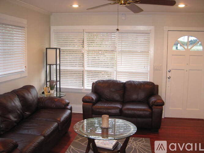 A living room with a brown leather couch and a glass coffee table.