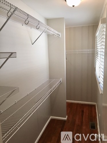 A walk-in closet with white shelving and a wooden floor.