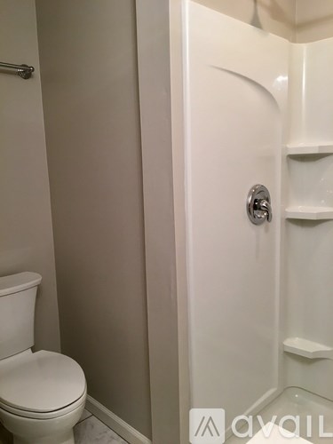 A white toilet in a bathroom with a white shower stall.