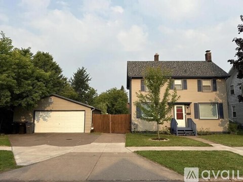A house with a garage and a tree in front of it.