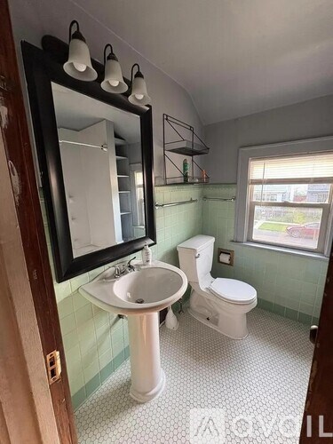 A bathroom with a toilet, sink, and mirror.