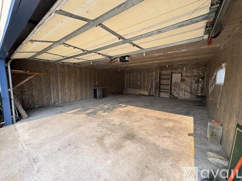 A large, empty room with a concrete floor and walls covered in insulation material.