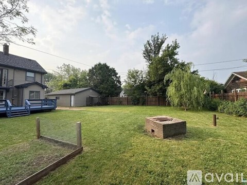 A backyard with a wooden fence, a tree, and a small wooden structure.