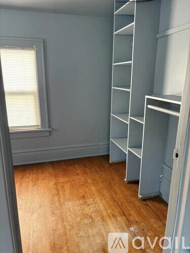 A room with a wooden floor and a window with blinds.