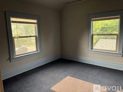 A room with two windows and a carpet on the floor.
