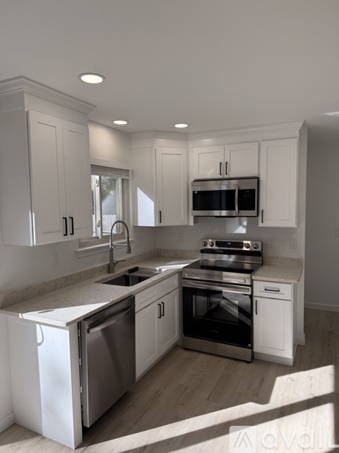 A modern kitchen with white cabinets and stainless steel appliances.
