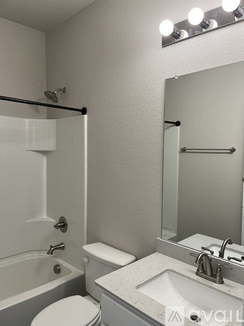 A white bathroom with a toilet, sink, and mirror.