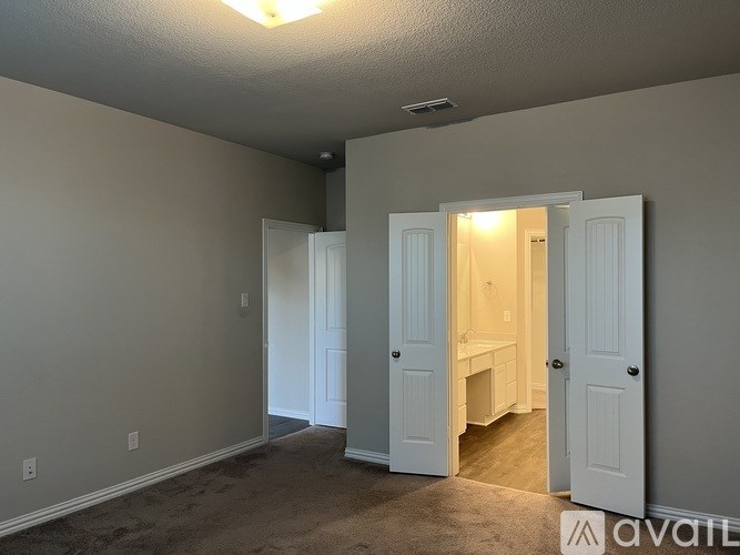 A room with two doors, one open, showing a bathroom.