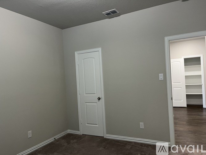 A room with a white door and a white shelf in the background.
