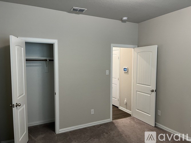 A room with two doors, one of which is open, and a carpeted floor.