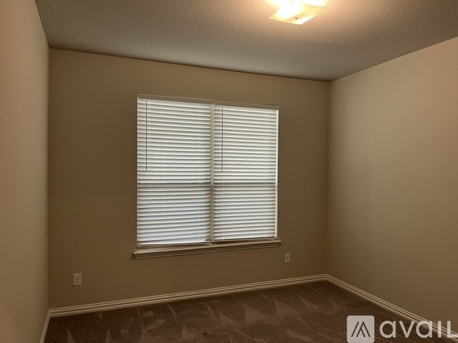A room with a window covered by white blinds.